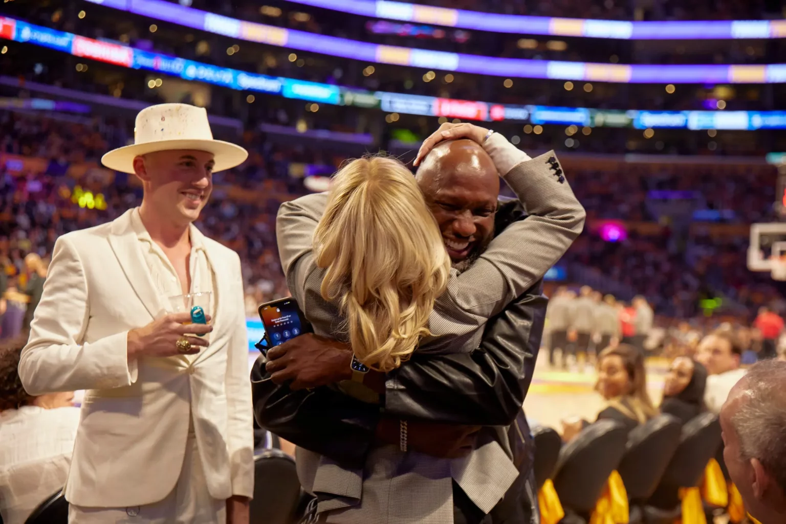 Ms. Buss’s nephew Riley Buss-Drexel looked on as she hugged the former Lakers power forward Lamar Odom at an October home game.Credit…Magdalena Wosinka