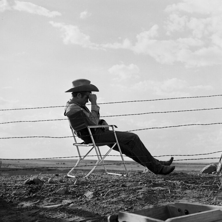 James Dean sitting in a chair wearing a cowboy hat