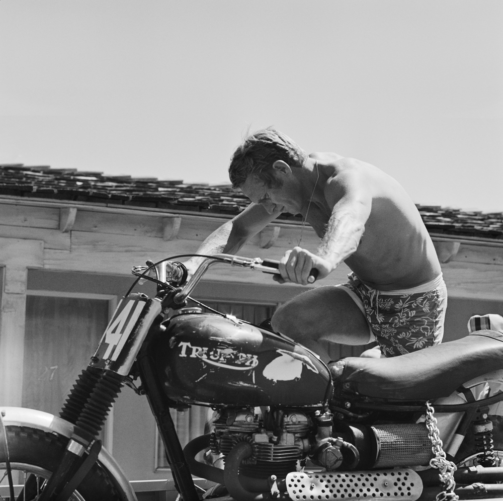 Steve McQueen starting a motorcycle
